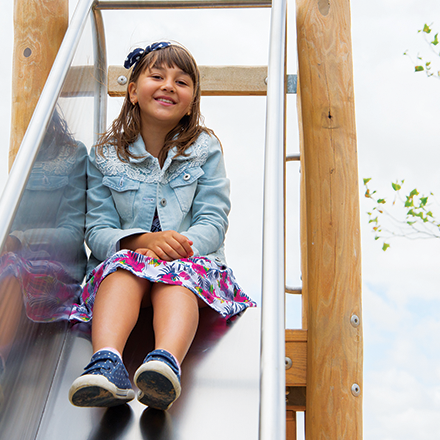 Girl sitting at the top of a slide